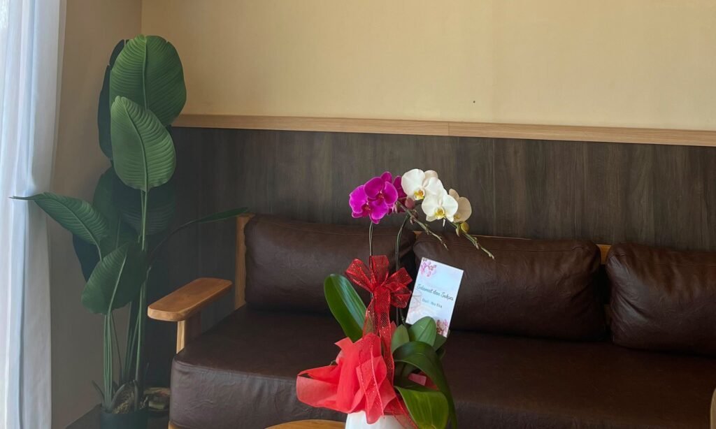 Leather sofa, banana-leaf plant and an orchid arrangement in the waiting corner