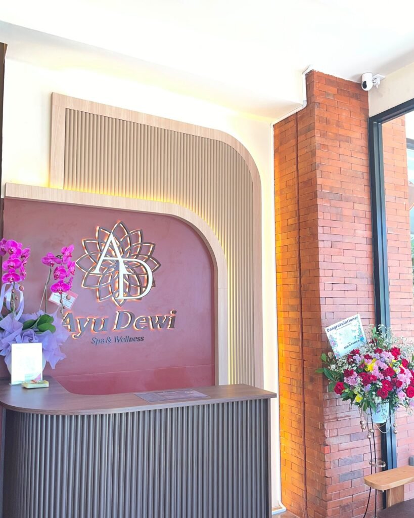 The Ayu Dewi Spa reception counter with orchids, a brick pillar and a flower stand