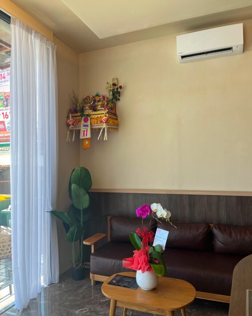 Waiting corner with a leather sofa, plant and a Balinese offering shrine